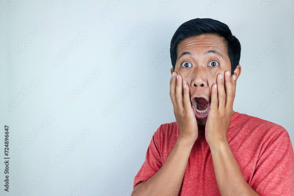 funny expression of shocked and surprised Asian man wearing a red t-shirt looking at the camera funny expression of shocked and surprised Asian man wearing a red t-shirt looking at the camera