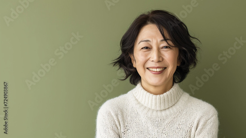  Happy Asian Woman. Portrait of Beautiful Older Mid Aged Mature Smiling Woman Isolated on Olive Green Background. Anti-aging Skin Care Face Beauty Product. Banner with Copy Space.