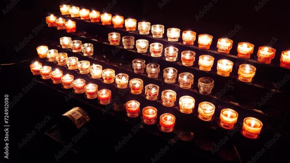 Bunch of small spot candle burning and glowing inside dark church altar room. Real time, no people Bunch of small spot candle burning and glowing inside dark church altar room. Real time, no people