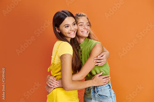 cheerful adorable teenage girls in casual outfits posing together and looking away, friendship day