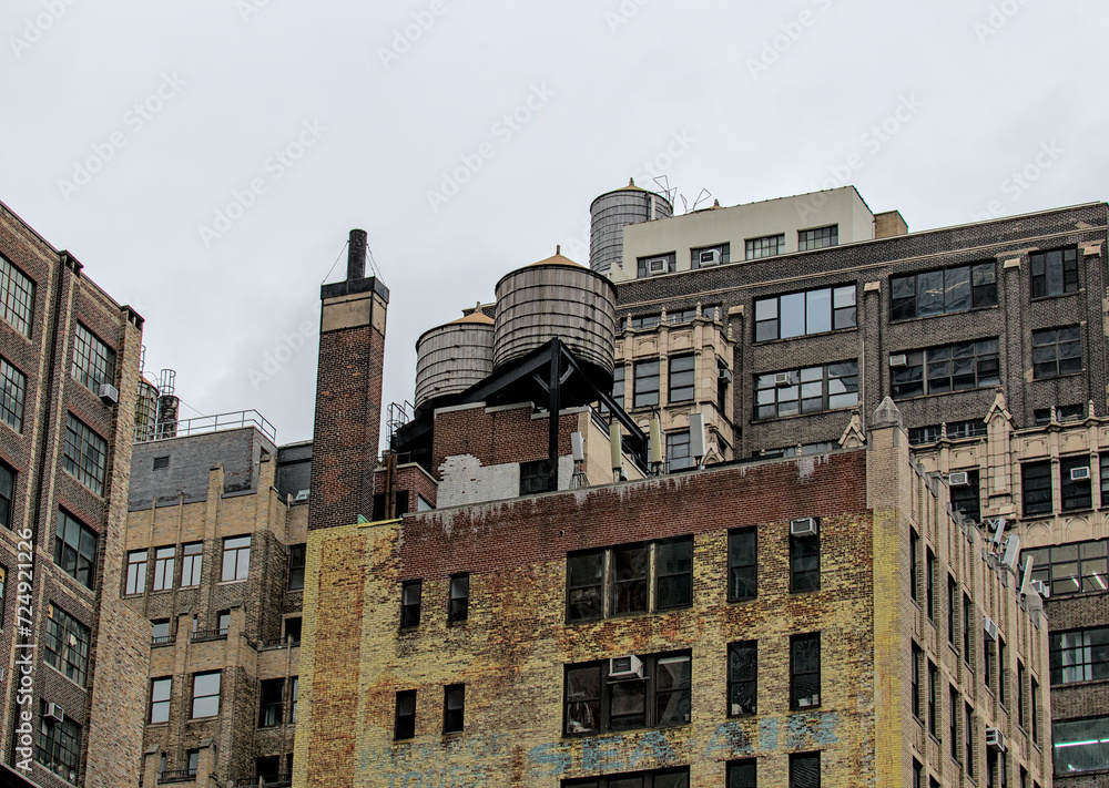 Fototapeta premium water coolers on top of old brick buildings in manhattan, new york city (hydration, fire, tower) iconic NYC towers for holding liquid
