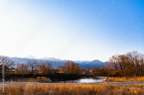 重光の池と冠雪した山岳風景 