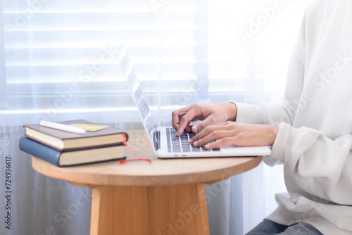 Woman wearing white shirt typing work on laptop on desk