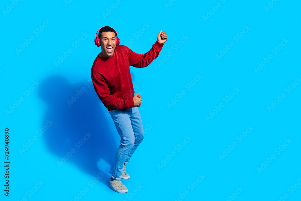Photo of positive funny man wear red trendy pullover enjoy vibe chill listen music wireless earphones isolated on blue color background