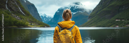 Young female hiker with a backpack admiring scenic view of spectacular Norwegian nature. Breathtaking landscape of Norway. Hiking by foot. photo