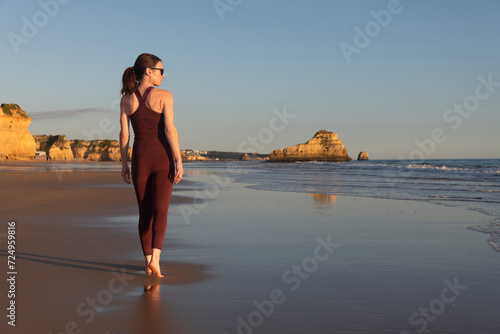 Sporty female walking barefoot along the beach