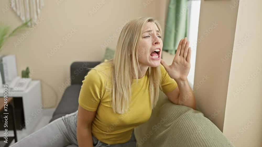 Furious young blonde woman at home, communicating rage, shouting and screaming loudly to the side with hand amplifying the message from her mouth. Furious young blonde woman at home, communicating rage, shouting and screaming loudly to the side with hand amplifying the message from her mouth.