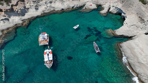 Aerial drone photo of beautiful crystal clear turquoise beach and cave formations visited by yachts and sail boats in Southern part of Antiparos island, Cyclades, Greece