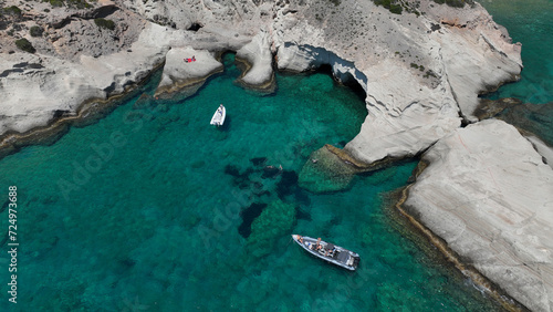 Aerial drone photo of beautiful crystal clear turquoise beach and cave formations visited by yachts and sail boats in Southern part of Antiparos island, Cyclades, Greece