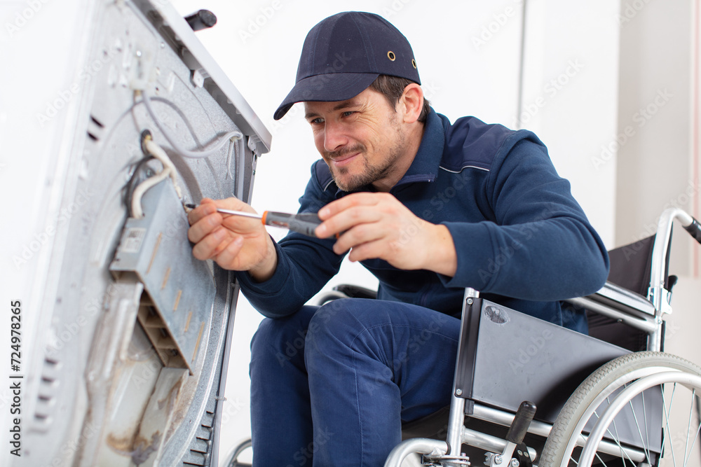 disabled working man plumber repairs a washing machine in laundry disabled working man plumber repairs a washing machine in laundry