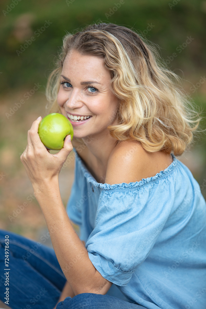 happy smiling young woman eating organic apple at her garden happy smiling young woman eating organic apple at her garden