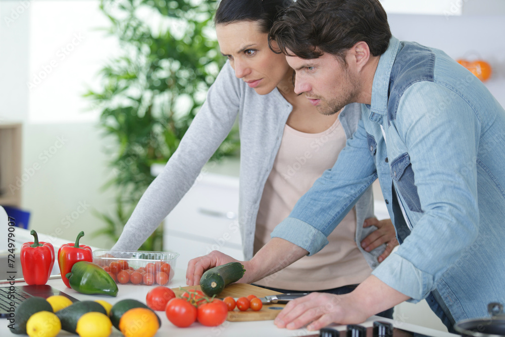 couple using laptop to look up recipe for their meal couple using laptop to look up recipe for their meal