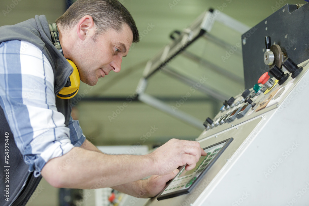 worker entering data in cnc machine at factory worker entering data in cnc machine at factory