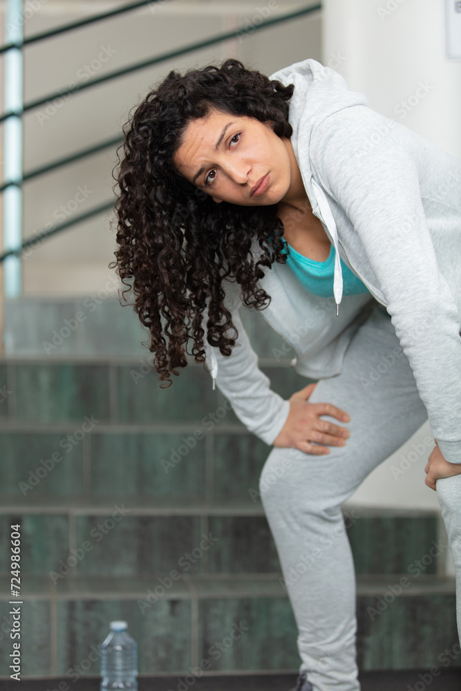 tired woman at bottom the stairs with bottle of water