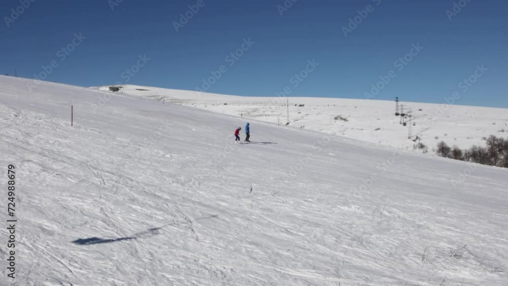 Two people go down the slope on a ski day on a sunny day Two people go down the slope on a ski day on a sunny day