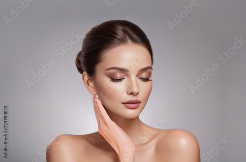 Beauty portrait of a beautiful half naked young woman touching her face. Skin care and cosmetics concept on gray background with copy space. 