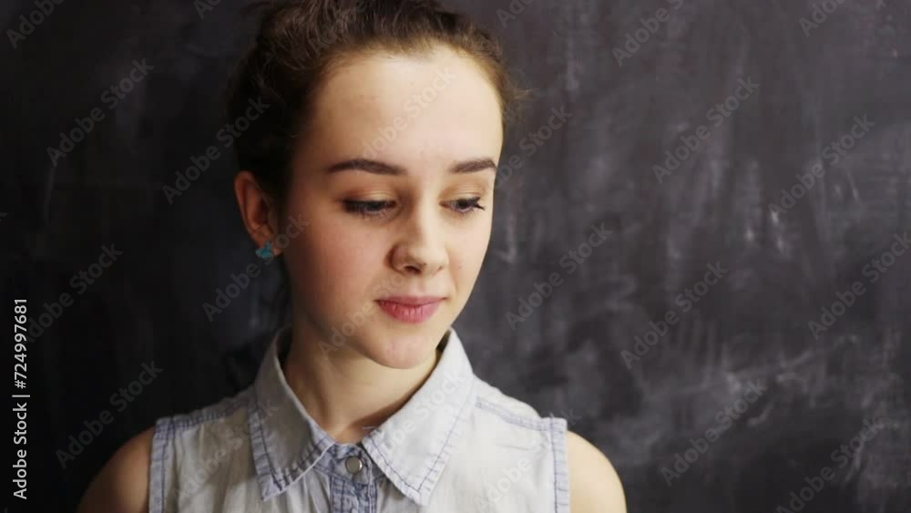Teenage girl stands at a gray wall, looks to the side Teenage girl stands at a gray wall, looks to the side