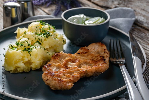 Pork chop served with mashed potatoes and cucumber salad.