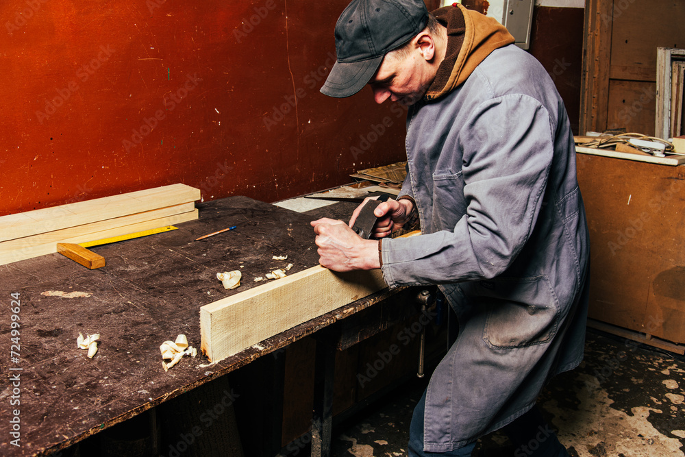 A carpenter works in a workshop with a saw, planer and various tools A carpenter works in a workshop with a saw, planer and various tools