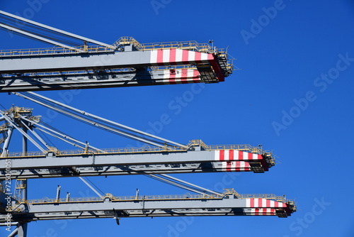 Low angle close up view of gantry cranes sticking against the blue sky waiting for handling ‘ship to shore’ containers photo