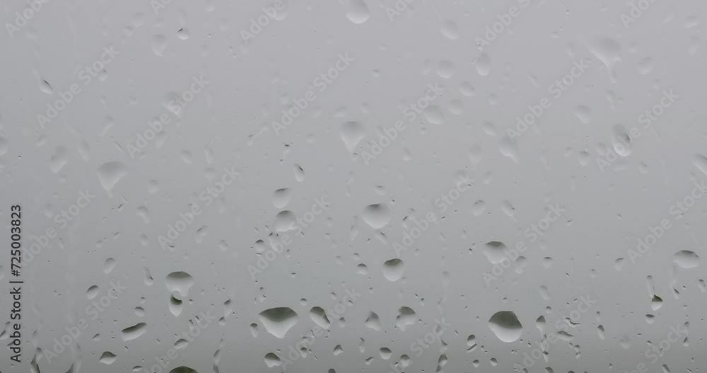 A raindrops on a window, with a green field and trees in the background. A raindrops on a window, with a green field and trees in the background.