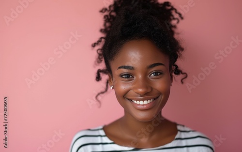 a smiling black woman in a striped shirt on a pink background