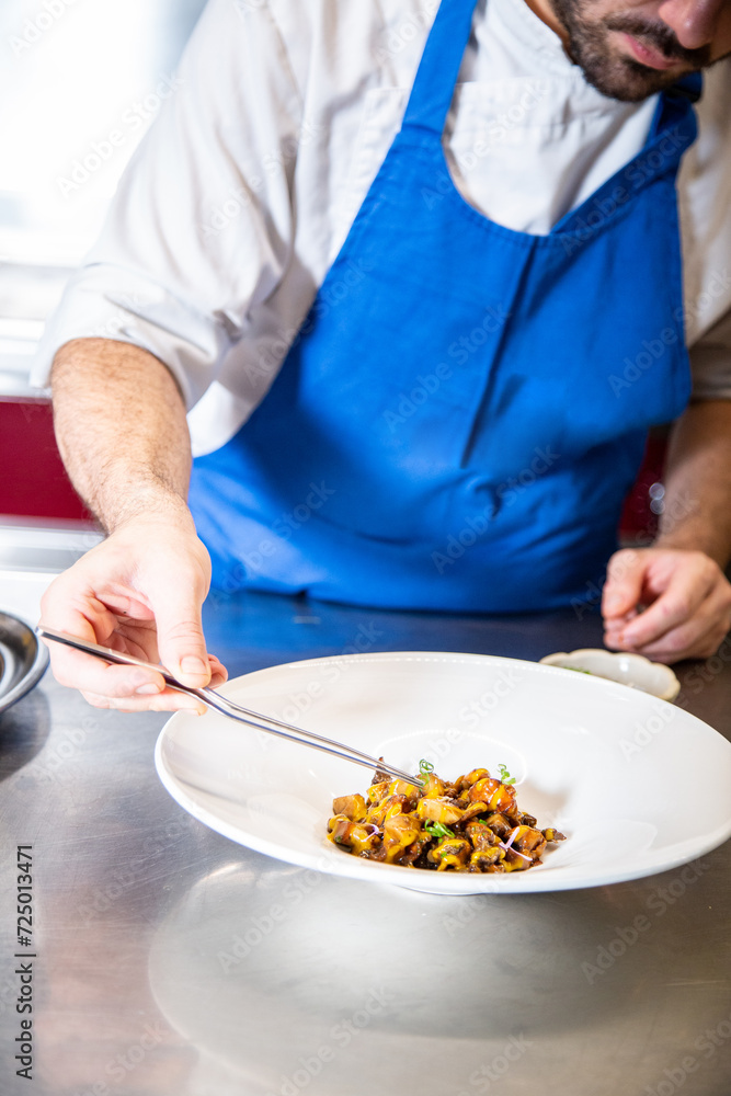 Chef prepara setas de temporada salteadas con yema de huevo curada con salsa de soja y flores decorativas sobre un plato de loza blanco Chef prepara setas de temporada salteadas con yema de huevo curada con salsa de soja y flores decorativas sobre un plato de loza blanco
