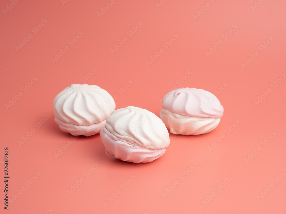 White and pink meringue cookies on a pink background. Meringue cookies close-up. White and pink meringue cookies on a pink background. Meringue cookies close-up.