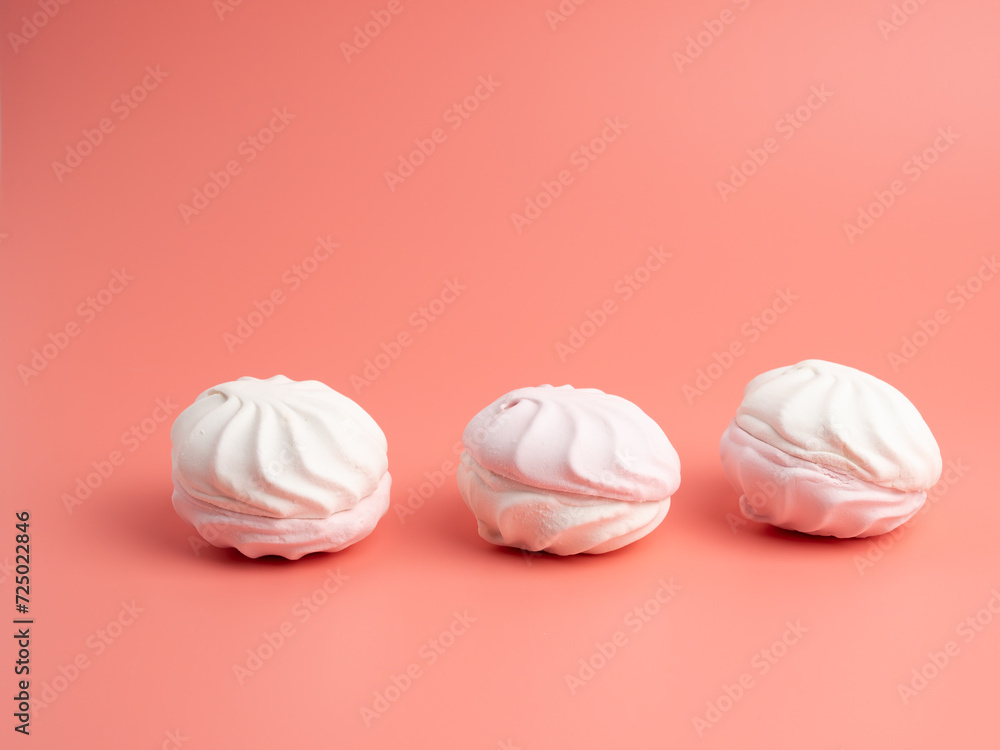 White and pink meringue cookies on a pink background. Meringue cookies close-up. White and pink meringue cookies on a pink background. Meringue cookies close-up.