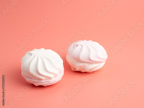 White and pink meringue cookies on a pink background. Meringue cookies close-up.