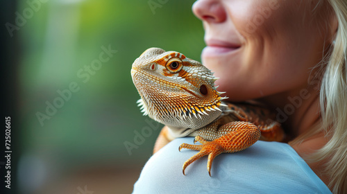 Bearded dragon lizard sitting on the shoulder of a woman photo