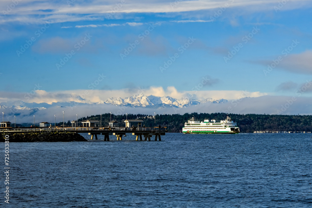 The Edmonds-Kingston Ferry in front of the Edmonds fishing dock, with the snowy Olympic Mountains in the distance, on a clear winter day