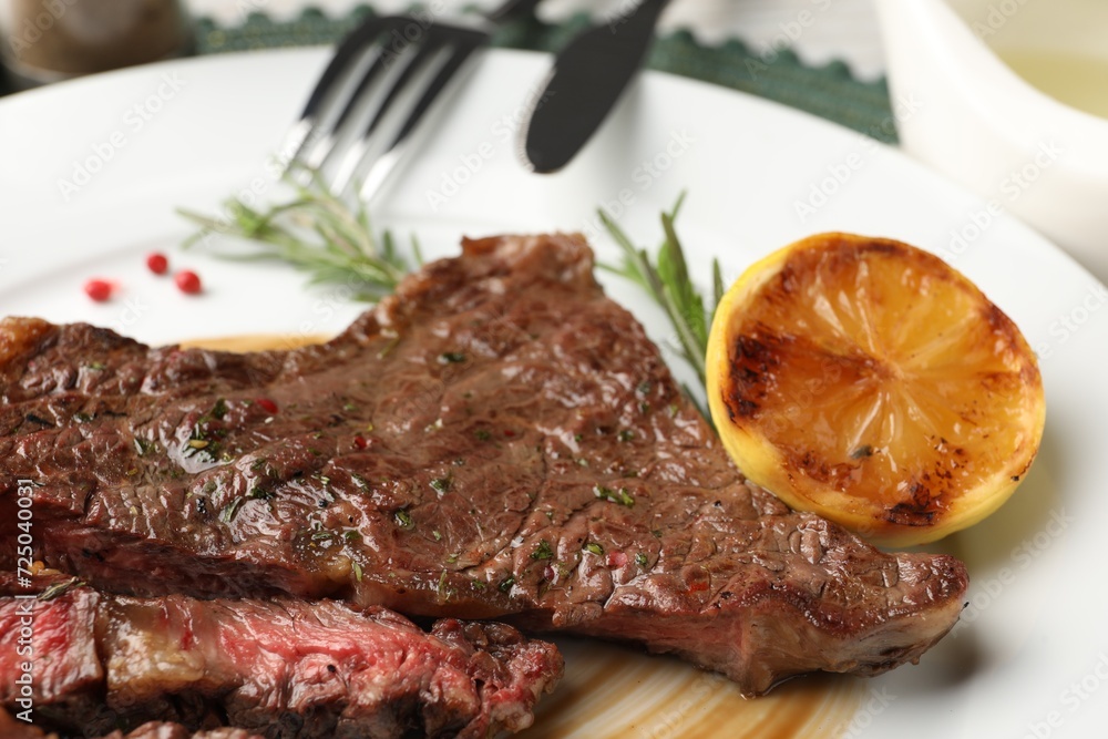 Delicious grilled beef steak with spices and lemon on plate, closeup Delicious grilled beef steak with spices and lemon on plate, closeup
