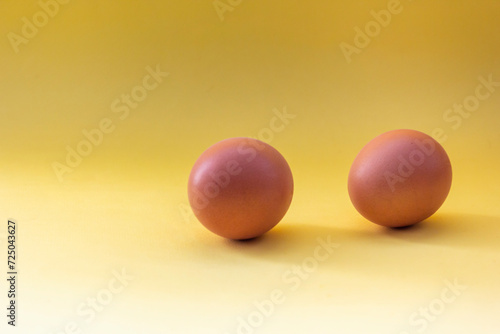 two chicken eggs isolate on a yellow background © Sviatlana
