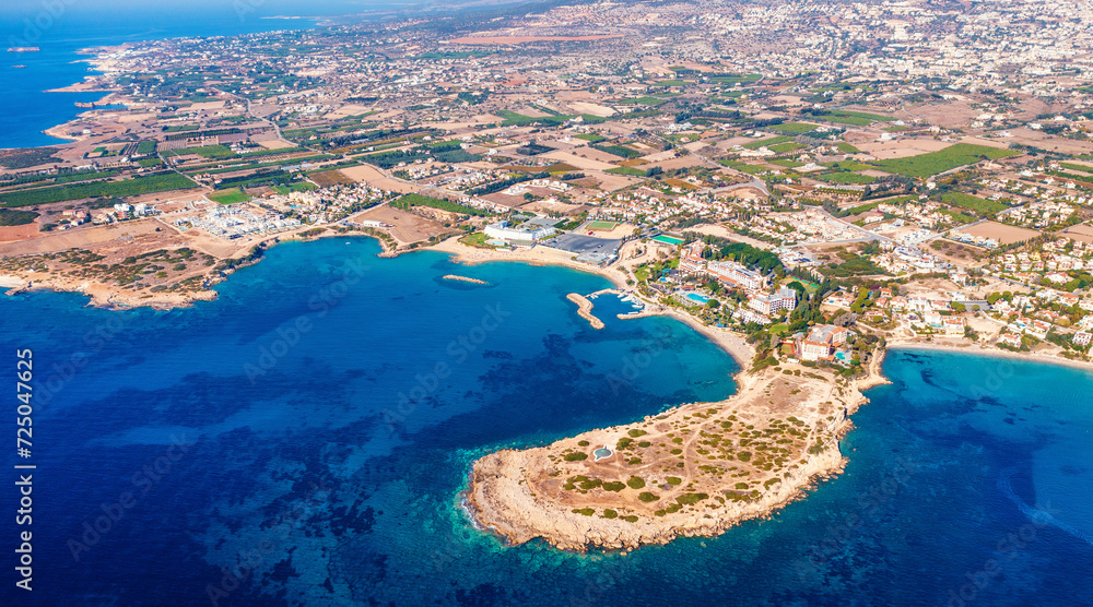 Aerial view of Cyprus coastal region with deep blue sea and rugged coastline with bay, hotel and beaches under bright sunlight