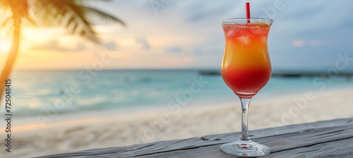 Refreshing tequila sunrise cocktail in tropical setting with blurred beach background and copy space