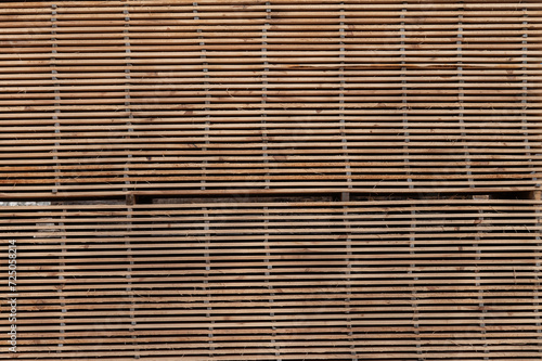 Stacks of boards, board flooring in a sawmill. Warehouse for cutting boards in a sawmill outdoors. Stack of wooden blanks construction material wood timber. Industry.