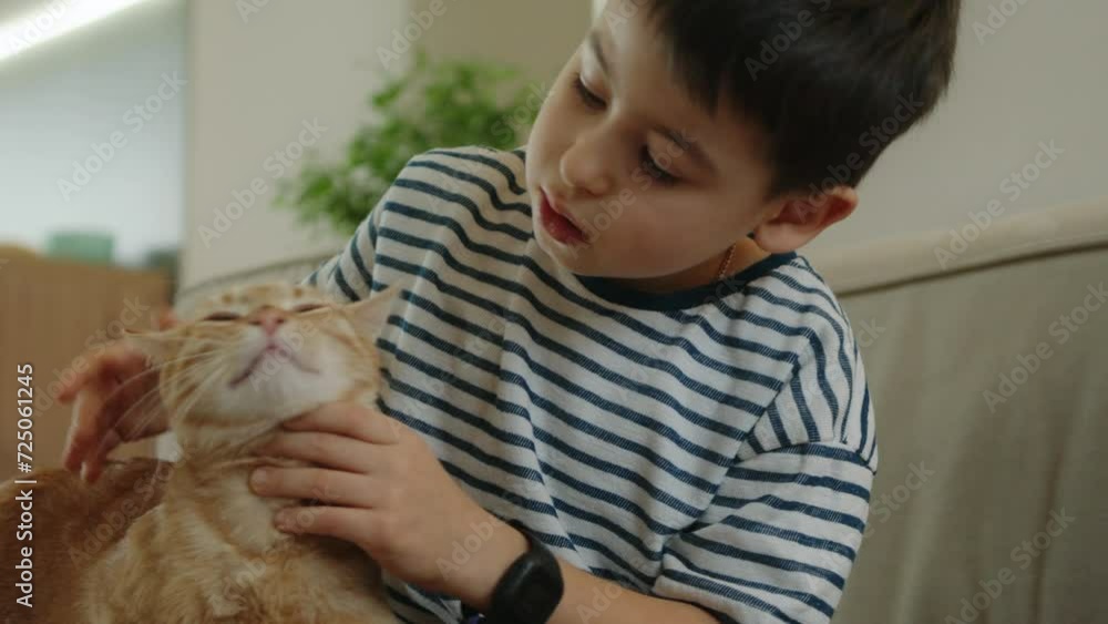 Adorable little boy caressing a red-haired cat indoors. Funny little pet kitten. Love and care Adorable little boy caressing a red-haired cat indoors. Funny little pet kitten. Love and care
