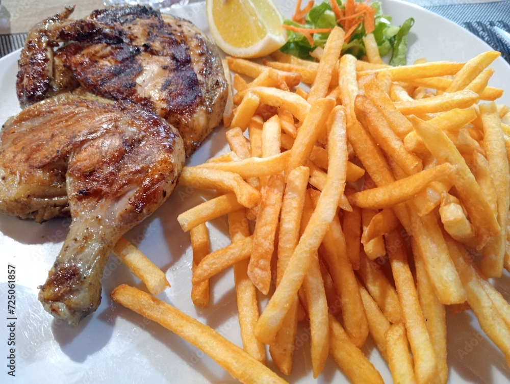 dish with half a grilled chicken and french fries