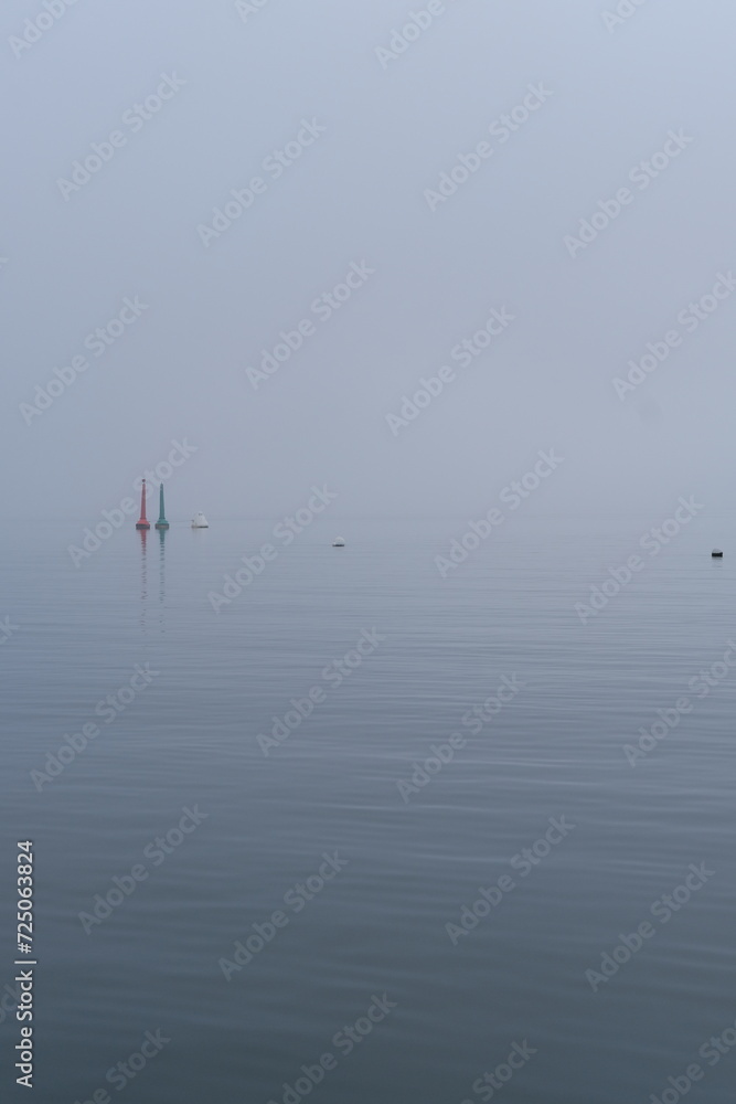 A red and green buoys together during a foggy day on the Arcachon bay. Cap Ferret, France - January 26, 2024. 