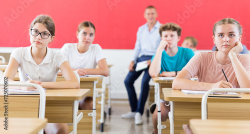 Group of teenage high school students diligently working in class, making notes of teacher lecture..