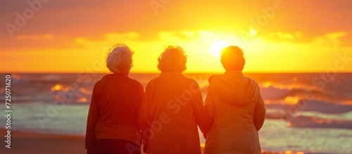 Three old female friends enjoy the beach\'s sunset.