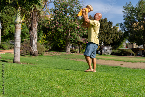 A happy father throws his son into the air in nature. The kid laughs merrily. A father walks with his son in the park.