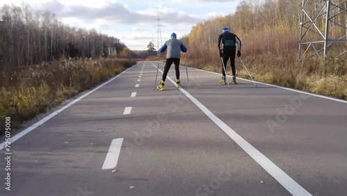 Back of two unrecognized man riding on roller skiing in park Losiny ostrov photo