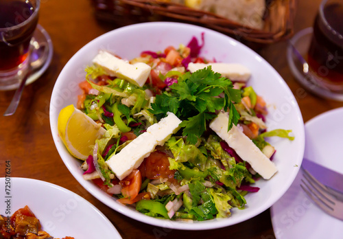 Healthy organic turkish choban salad with cheese, tomato, cucumber, herbs and lemon photo