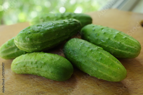 ripe green cucumbers on a wooden kitchen board. close-up