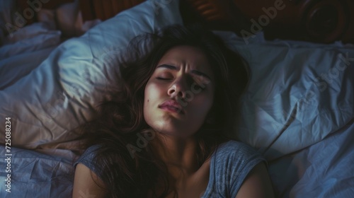 A peaceful portrait of a woman, enveloped in the warmth of her bedclothes, lost in comfortable slumber with her eyes closed and her delicate skin glowing in the soft indoor light © Radomir Jovanovic