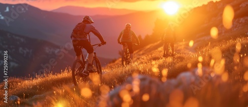 As the sun sets over the mountains, a group of adventurous individuals ride their bicycles up a hill, basking in the beauty of the outdoor sky photo