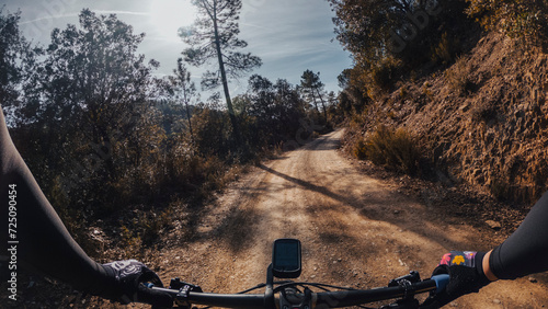 Riding amountain bike with wide handlebar and gps computer on a sandy forest path rider point of view photo