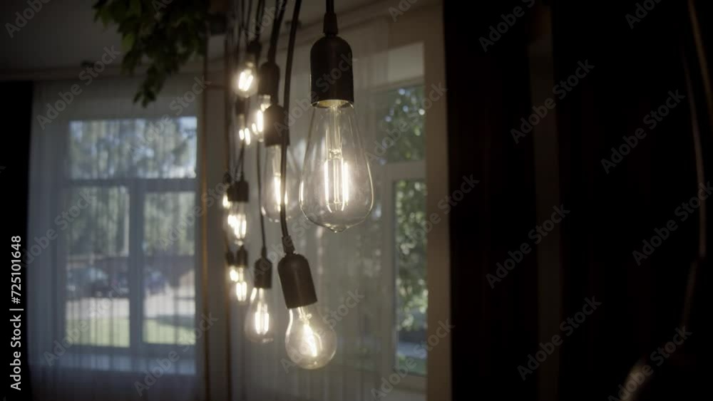 Swaying retro light bulbs in the room. Antique bulbs with old lamp holder are switched on. Group of light bulbs stringed up in a dark room. Swaying retro light bulbs in the room. Antique bulbs with old lamp holder are switched on. Group of light bulbs stringed up in a dark room.